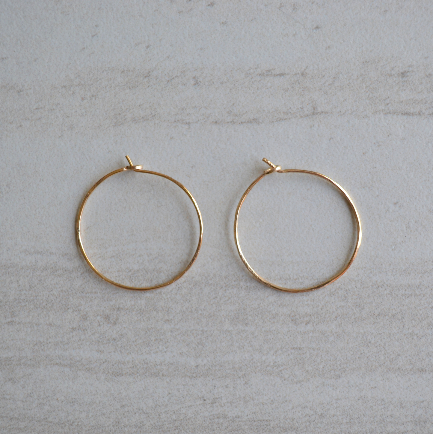 Gold hoop earrings on a light gray surface