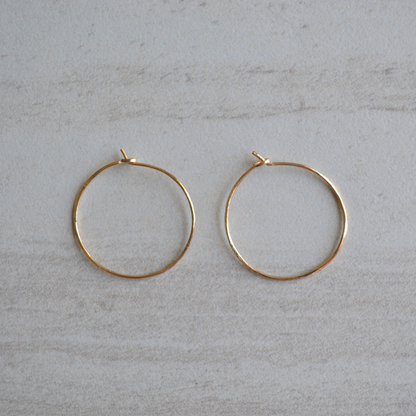 Gold hoop earrings on a light gray surface